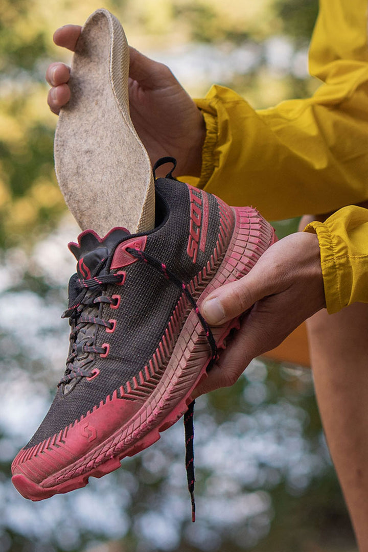 Ekser insole being put into a trail running shoe